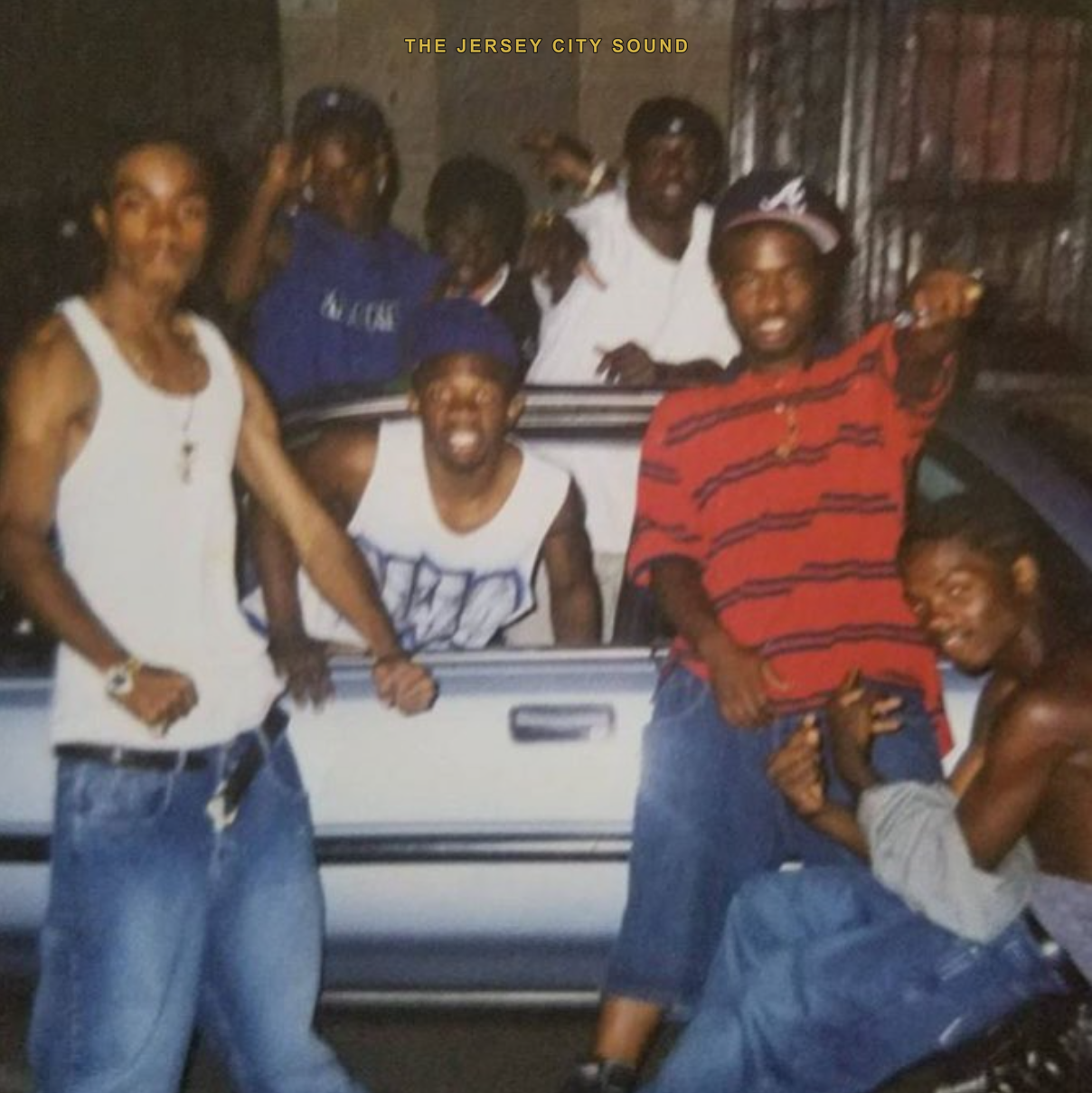 A crew posed around a car at night in the 1990s