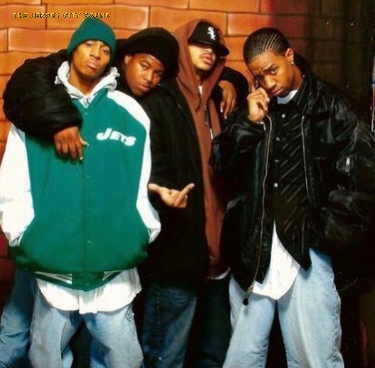 Four young men posed against a brick wall: DJ E Double, DJ Walley Katt, Meech, and DJ Thunderkatt