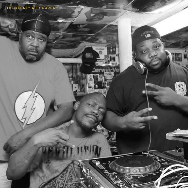 DJ Wimpy Bee in a lightning bolt shirt with DJ Sinister and DJ Hardcore at a record filled basement