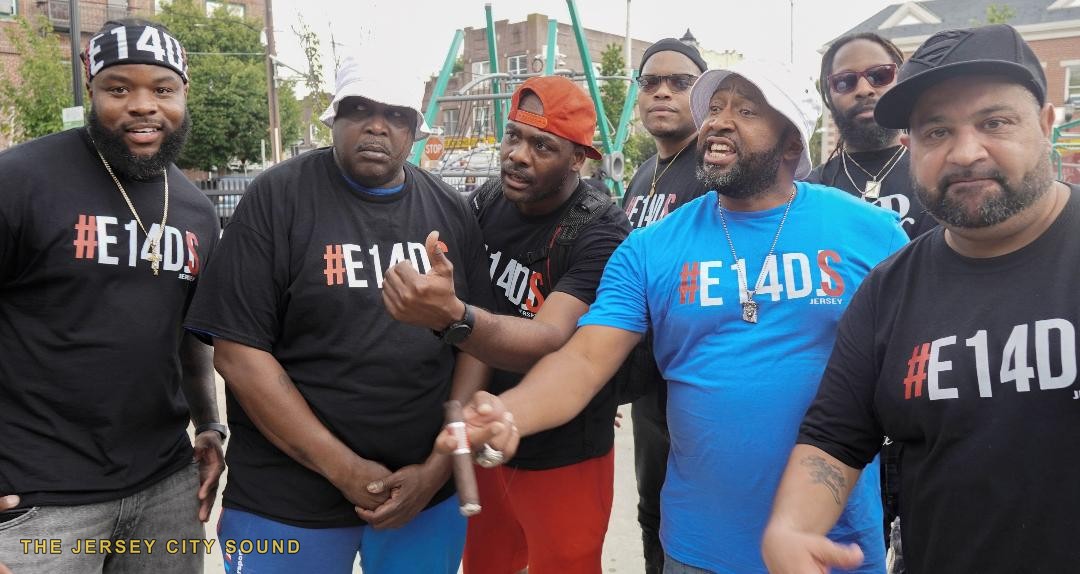 Seven members of Exit 14 DJs in E14DJS shirts talking at the park